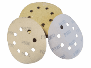 Close-up of a stack of velcro type sanding disc, with holes for dust collection